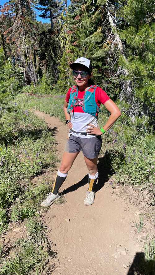 Female trail runner with legs covered covered in dirt posing on trail at Ragnar Trail Tahoe.